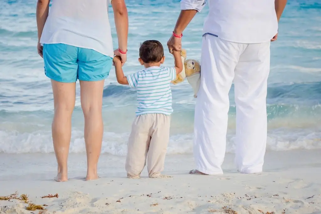 Familia caminando de la mano en la orilla de la playa